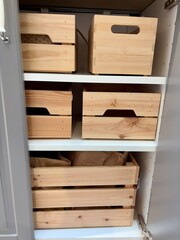 Organized wooden crates inside a kitchen cabinet for efficient storage and a clean