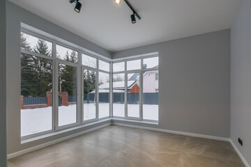 A room without furniture, on the ground floor of a country house. Panoramic windows with a view of the winter landscape.
