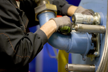 Industrial Heating System Maintenance – Close-Up of Technician Adjusting Pipes and Valves for...