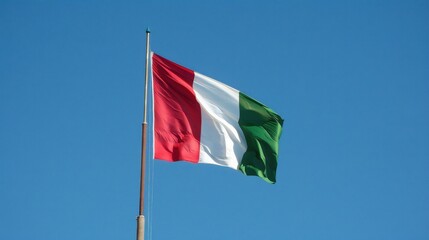 Italian national flag waving against a clear blue sky on a sunny day