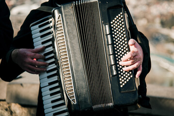 Man play keys accordion, musician guitarist performs at concert outside