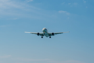 A blue sky background with an airplane prepared for landing on a well known place for plane spotter at Mao Khao Beach, Phuket, Thailand