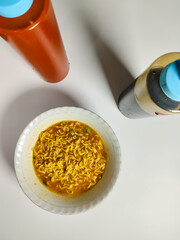 close up of a bowl of spicy noodle soup with spicy chili sauce and sweet soy sauce isolated on white