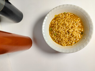 close up of a bowl of spicy noodle soup with spicy chili sauce and sweet soy sauce isolated on white