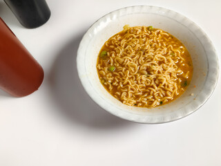 close up of a bowl of spicy noodle soup with spicy chili sauce and sweet soy sauce isolated on white