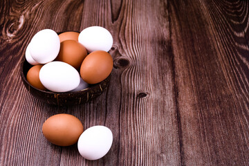 brown and white eggs in a bowl on a wooden table. eggs near a bowl