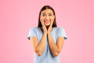 Portrait of excited lady touching cheek with joy isolated over orange studio wall, looking at camera, copyspace