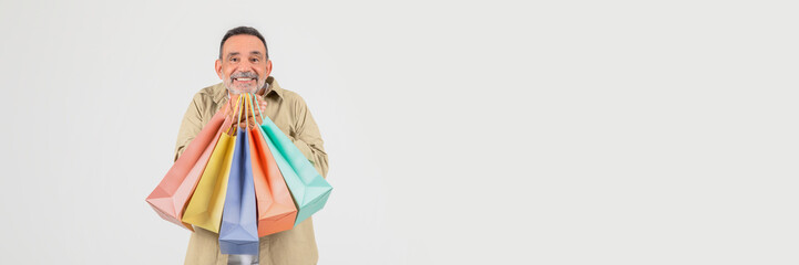 An elderly man beams with joy holding colorful shopping bags, suggesting a successful retail experience, isolated on a white background