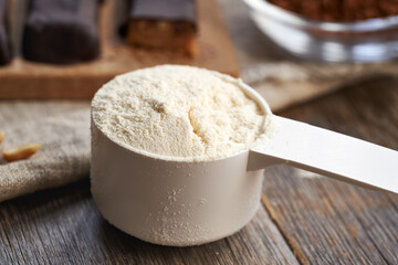 A scoop of whey protein powder with homemade healthy chocolate bars and raw cacao in the background