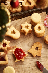 Filling bell shaped Linzer Christmas cookie with strawberry marmalade