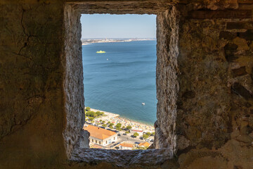 Looking out through a granite window over the ocean and beach from a mountaintop fortress in Setubal.