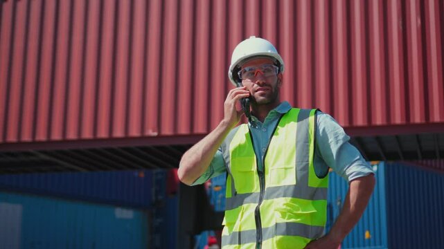 Handsome Caucasian dock container yard manager use phone to work in container terminal.
