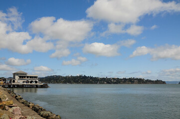 Fototapeta premium Saisalito, CA, USA. April 26, 2012: Scenic view of Sausalito waterfront with pier and hills under a blue sky.