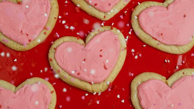 Valentine's Day sprinkles falling onto heart shaped cookies in slow motion.