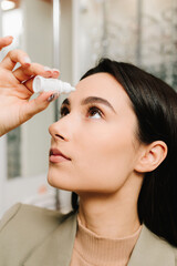 Eye treatment from suffering irritation and inflammation in the optic clinic. Applying eye drops to...