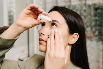Girl using eye drops for treating dry eye. Young woman puts drops in her eyes. Treatment for eyesight correction.