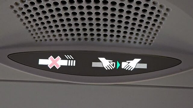 Airplane seatbelt and no smoking sign indicator panel with illuminated icons. Interior cabin detail for passenger safety. Close-up view.