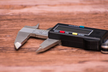 Digital caliper lies on a wooden surface, featuring a sleek black and silver design with a clear...