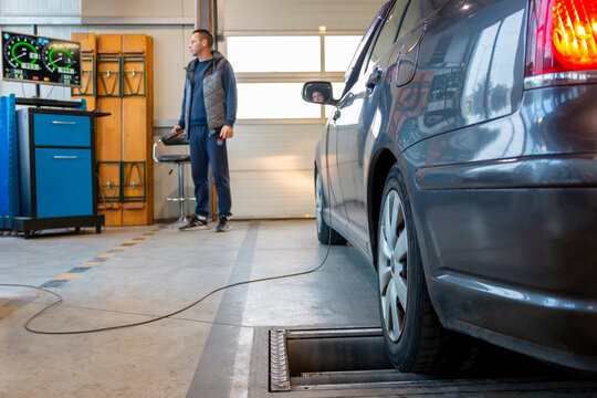 Car on brake tester machine. Inspection lane in car technical control station. Annual vehicle inspection before the car registration. Automotive safety concept.