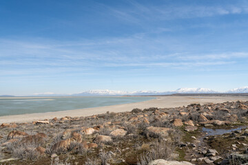 Obraz premium Rocky Shoreline and Snow-Capped Mountains at Antelope Island State Park.