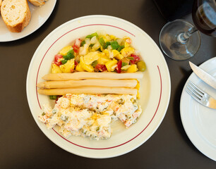 Traditional Spanish summer salad of potatoes, tomatoes, greens, olives, Russian salad dressed with mayonnaise and white asparagus served on plate