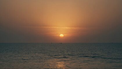 Obraz premium Sunset over the ocean with gentle waves and distant boats on the horizon