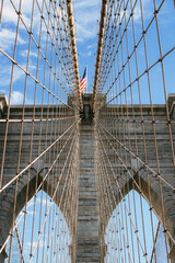 Obraz premium Seilstruktur und Pfeiler der Brooklyn Bridge mit amerikanischer Flagge