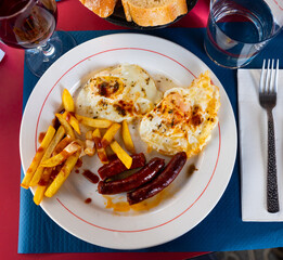 Popular dish of Spanish cuisine is fried eggs with chistorra and potatoes, drizzled with sauce on...