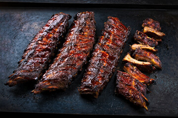 Charcoal smoked barbecue spareribs St Louis cut with hot rub and BBQ sauce served on an old rustic board