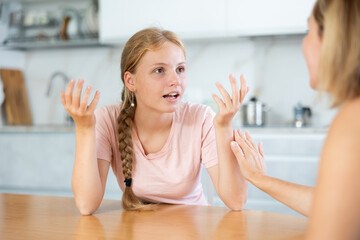 Teenage daughter enthusiastically happily tells unrecognizable mother about planned vacation with...