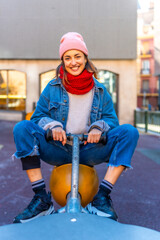 Young woman having fun on a playground rocker in winter city setting