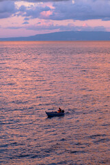Piccola barca in mare al tramonto colore roseo