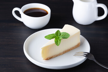 Delicious slice of cheesecake with mint garnish served alongside a cup of coffee for a delightful dessert experience