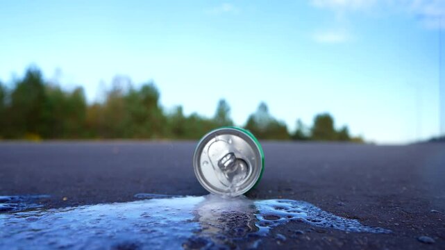 Crumpled soda can on asphalt with drink spilled. Discarded broken carbonated drink tin can on asphalt road. Problem social, crime. Thrown out Crushed juce. Crumpled Beer Can Crushed. Spilled drink.