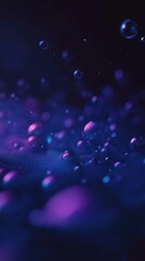 Abstract close-up of colorful water bubbles illuminated with purple and blue light in a dark setting, perfect for artistic and modern backgrounds or illustrations