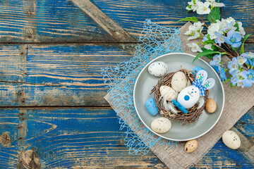 Easter table setting with eggs, bird's nest and blooming branch. Traditional festive symbols