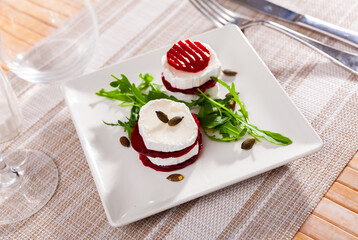 Salad with pieces of goat cheese, boiled beets and arugula