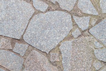 Close-up image of weathered, irregular stone surface with cracks and a lighter patch in the lower right corner The focus is on texture and material properties