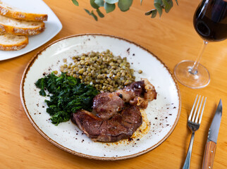 Delicious fried beef pieces served with spinach and lentils on plate
