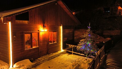 Wooden house with winter view, christmas concept, glowing wooden hut in snowy forest