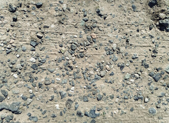 Pieces of old concrete, slag and gravel in the form of small gray stones, view from above. Old road surface, transformed by time and temperature changes into ruins. Dirt road.