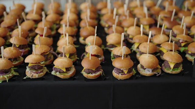 mini hamburgers arranged in rows, catering service at the event