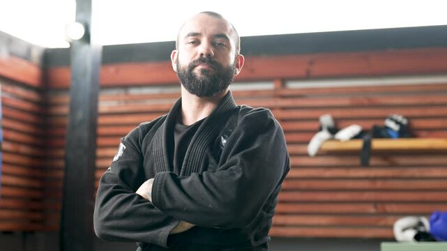 Confident jiu-jitsu athlete flexing biceps in gym