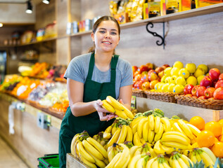 Saleswoman near fruit and vegetables stalls offering to buy bananas