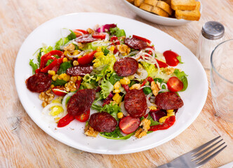 There are large pieces of fresh vegetables and sliced chorizo sausage on plate. Vitamin salad of fresh vegetables, china cabbage, corn, chorizo and Bulgarian pepper