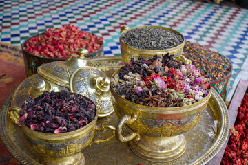 Golden bowls at street stalls in Marrakech with different spices, teas and incense