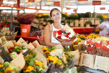 Glad young woman choosing bouquet of flowers in point of sale of plants