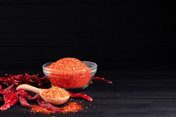 Chili powder, dried chilies, spicy condiments in a bowl placed on a table, dark background.