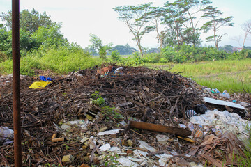 piles of tree branches and plastic waste piled up on the edge of the rice fields
