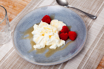 Mato, fresh whey cheese of Catalonia, served on plate with raspberries and honey. Tradicional Spanish dish.